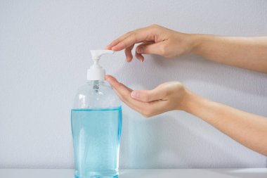 Hijyenik kavramda beyaz arka planda ellerini yıkamak için alkol antiseptik jel kullanan kadınların yakın çekim elleri