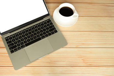 Boş bir dizüstü bilgisayar ve tahta arka planda bir fincan kahve.