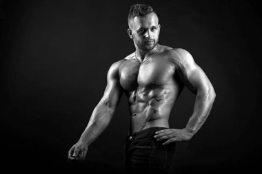 Genç seksi erkek fitness modeli gösteren mükemmel vücut izole siyah arka plan siyah ve beyaz resim üzerinde teşkil etmektedir.