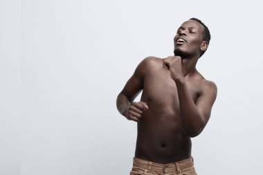 Yakışıklı Afro-Amerikan koyu tenli adam dans kendisi ve güzellik ile atletik vücudunun olmaktan zevk gözleri kapalı. Gri studio duvara gömleksiz taşıma