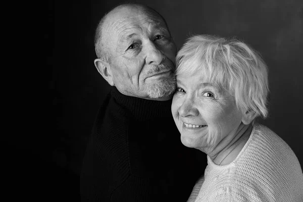 When two become one. The head studio shot of senior couple, looking and smiling at the camera. Black and white image with copy space area for your advertising messages or content on dark background