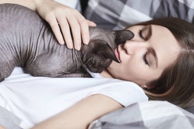 Uyuyan güzel. Genç çekici mükemmel tenli Bayan göğsüne yalan bir Sfenks kedisi olan kış portresi kapatın. Rahatlık, eğlence, ev concept.