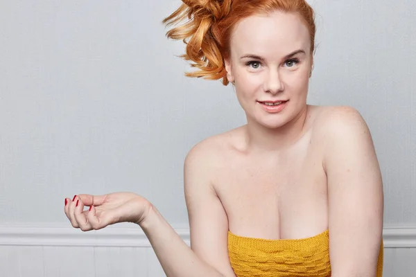 Human face expressions, emotions and feelings. Closeup studio portrait of beautiful young cheerful Caucasian redhead freckled woman looking playfully at the camera demonstrating something on grey wall with copy advertising space.