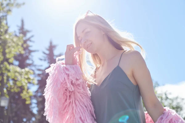 Persone, viaggi, vacanze e svago concettuale.Vista posteriore di giovane donna con lunghi capelli sciolti che passeggia nel parco avventura alla luce del sole indossando occhiali e cappotto, godendo felice piacevole momento di vacanze . — Foto Stock