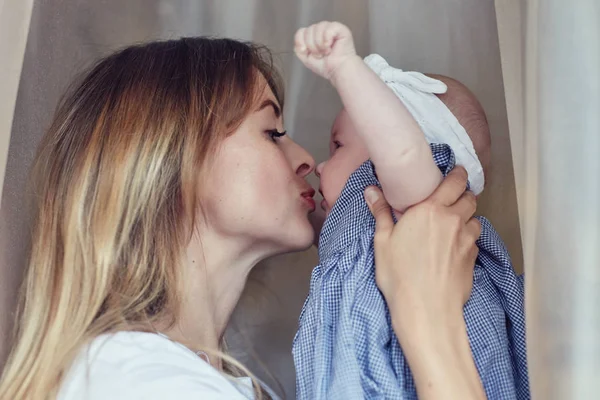 Giovane e bella madre caucasica e bambino in casa. Felice ritratto di famiglia. Un primo piano di mamma moderna e suo figlio che giocano a casa. Amare mamma baciare e guardare il suo prezioso bambino . — Foto Stock