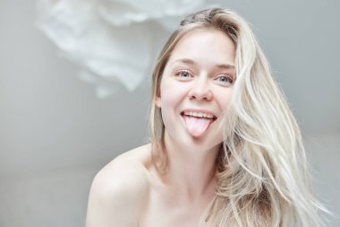 İhale kapalı yakın çekim portre onun sabah yatakta mutlu gülümseme ile poz güzel beyaz kadın. Genç çekici gözlü Bayan şakacı kameraya bakarak uzun sarı saçlı mavi. Sağlık ve güzellik kavramı.