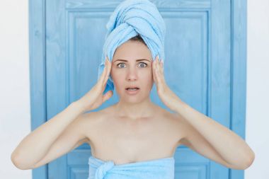 Aman Tanrım! Shoked ya da korkmuş bak, genç beyaz mavi gözlü ev hanımı başında onun tapınaklar, ellerinde tutmak duş sonra havlu ile sahip önemli bir şey yapmayı unuttum. İnsan yüz ifadeleri ve duygular.