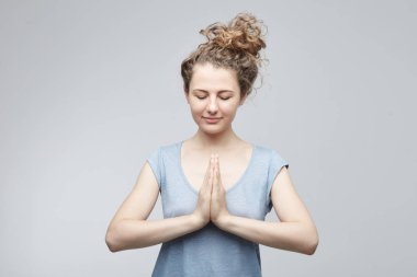 Meditasyon ve dua kavramı. Beyaz kadın duran kapalı gözler ve sakin yüz iç barış ve dua elele bilgelik dolu beyaz duvara meditative poz.