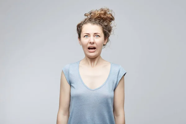 Oh, no. Desesperada estresada joven atractiva mujer de ojos azules mirando a la cámara en el terror y el shock con los ojos salió y abrió la boca con mirada preocupada y asustada. Concepto de personas y emociones . — Foto de Stock