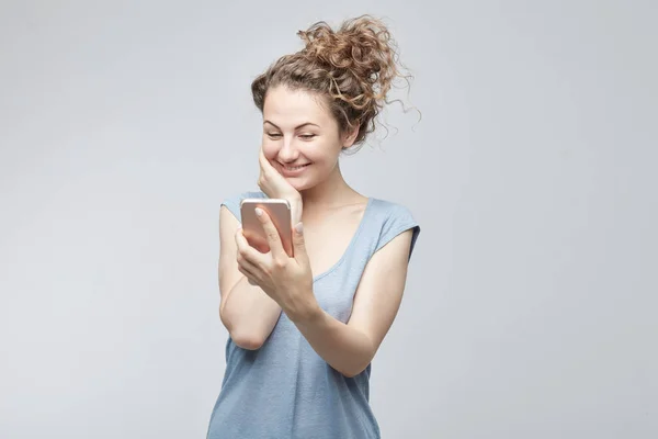 Primer plano retrato sonriendo o riendo joven freelancer mujer mirando el teléfono viendo buenas noticias o fotos con buena emoción en su cara aislado fondo de la pared. Emoción humana, reacción, expresión . —  Fotos de Stock