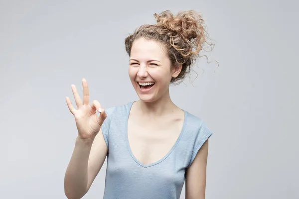 Gelukkig aantrekkelijke dame gekleed casual met krullend haar in bun ogen sluiten met vreugde weergegeven: ok teken wordt blij na sollicitatiegesprek geïsoleerd op witte achtergrond. Menselijke gezichtsuitdrukkingen en emoties. — Stockfoto