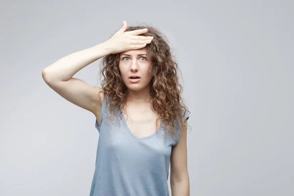 Expresiones y emociones del rostro humano. Mujer olvidadiza de piel blanca sosteniendo la mano sobre su cabeza con una expresión minuciosa mientras lucha por recordar algo. Linda estudiante mujer abofeteando frente . — Foto de Stock