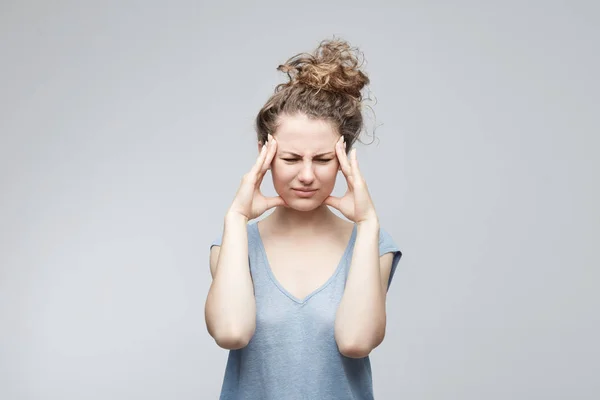 Mujer decepcionada tomándose de las manos en los templos, frunciendo el ceño, teniendo una mirada dolorosa, haciendo muecas, apretando templos, sufriendo de migraña o dolor de cabeza, sintiéndose estresada mientras enfrenta problemas en la universidad . — Foto de Stock