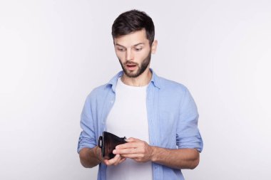 Yakışıklı genç beyaz adam stresli yüz ifadesiyle boş cüzdanını arıyorsunuz. Sakallı hippi bütçeyi olduğunu fark etti. Stüdyo çekim izole iş, beyaz arka plan üzerinde para, duygular.