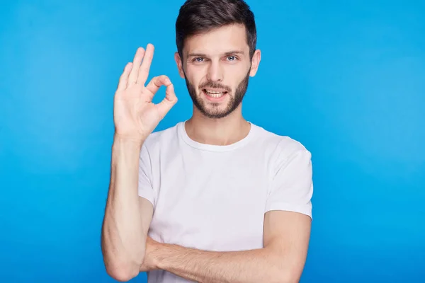 Retrato de hombre barbudo atractivo con estilo alegre con muestra signo ok expresando su acuerdo. Joven hombre de negocios guapo mostrando su éxito y regocijando su triunfo en el trabajo haciendo gestos en cámara . — Foto de Stock