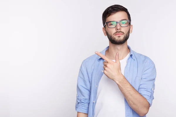 Concepto publicitario. Retrato del empresario caucásico guapo o trabajador de oficina que usa ropa casual señalando con el dedo la pared blanca del estudio con espacio para copiar su contenido contra la pared de hormigón — Foto de Stock