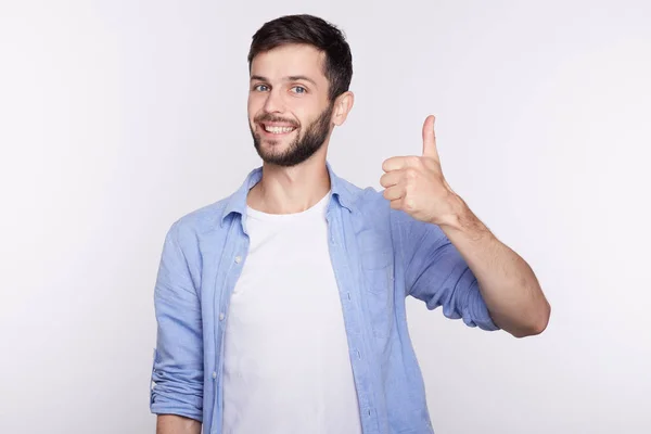 Retrato de un joven y feliz estudiante caucásico exitoso que da un gesto de pulgar hacia arriba con plena confianza aislado en el fondo de la pared del estudio. Emoción humana positiva, expresión facial, lenguaje corporal . — Foto de Stock