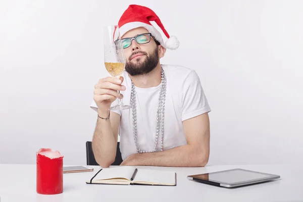 Merry Christmas and Happy New Year 2018! Young single sad and lonely overworked man is watching bubbles in the glass of champagne. Caucasian male suffering from loneliness at night time at the office