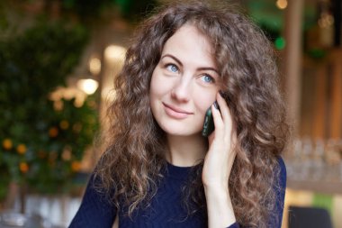 Güzel gözlü kadın rüya gibi göz smartphone gülümseme, onun arkadaşı duymak mutlu olmak modern kafede oturan parlayan ile iletişim holding ile mavi. İnsanlar, modern teknolojileri, iletişim kavramı.