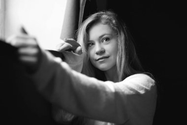 Siyah ve beyaz cam kenarında duran, kameraya bakarak, siyah duvar arka planı poz sevimli beyaz Bayan portresi. Reklam içeriğinin için kopya alanı olan güzel kadın kapalı atış.