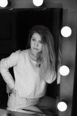 Dikey siyah ve beyaz portre genç Avrupa baştan çıkarıcı kadın aynaya bakarak yansıtıyordu. Uzun saçlı sarışın Bayan kendini, kayıtsızca, giyinmiş ciddi gizemli yüz ifadesi olan hayran.