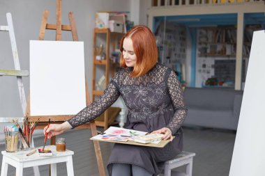 Yaratıcı erkek şövale ayakta onun atölyesinde fırça darbeleri yapma farklı renkli yağlar ile çevrili. Yetenekli ressam Resim Sanat stüdyosu suluboya ve boya fırçası kullanarak çizim.