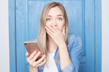 Moda stresli genç erkek şok ağzına kapsar, çok duygusal olmak yolu ile sms, önemli bir mesaj var, büyük hata anlar, kamera pişman dik dik bakıyor, beyaz duvar izole. Beden dili.