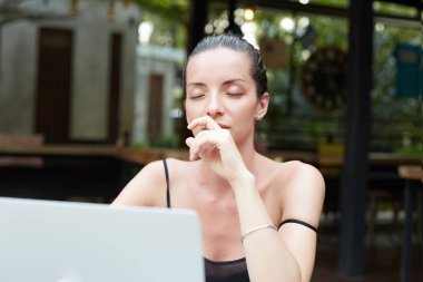 Kadın metin yazarı işleri uzaktan, modern dizüstü kullanarak meditasyon lezzetli içecek sahiptir, iyi bir internet bağlantısı kullanır. Kadın konsantre çalışıyor, gözlerini kapatmak, yeni fikirleri araştırma kafede.