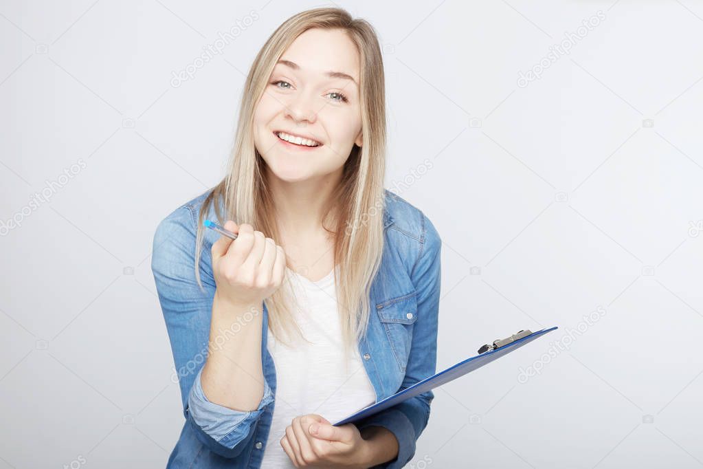Portrait of positive female copywriter works alone, writes notes, brainstorming, creating new article in foreign magazine. Clever student prepares report in English literature isolated on white wall.