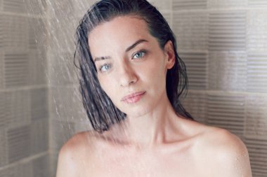 Su damlaları kameradan bakıyorsun nefes kesen karışık koştu genç esmer kadın portresi kapatın. Tuğla banyo duvar üzerinde izole duş alırken beyaz kadının şehvetli kafa vurdu.