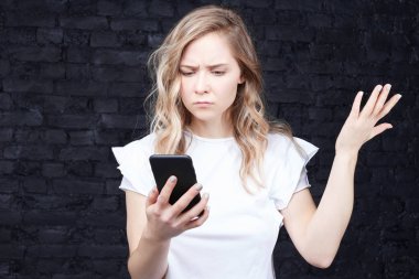 Sinirli çekici kadın hareketleri, rahatsız edici bir mesaj aldığında somurtkan surat, dişlerini sıkan, cep telefonuna bakan, siyah duvarın üzerinden izole edilmiş. Aletle taciz edilmiş ya da rahatsız edilmiş bir kadın..