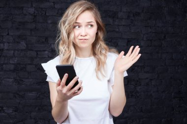 İnsan ve teknoloji. İnsanlar, eğitim kavramı. Internet üzerinden telefon bilgilerini kontrol bazı şüpheleri sınıf öğrenim rahat kıyafetler güzel Avrupa kadın. Yüz ifadesi.