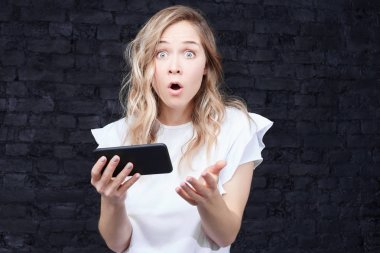 Raslantı iş ortakları ile önemli toplantı hakkında unutmak için şok video mesajı alma onun modern smartphone tutarak samimi sarı dalgalı saçları ile hayrete işkadını kadeh giyinmiş.