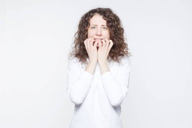 Korkmuş genç Avrupa kadın mavi dinleme cihazı gözlerle kameraya benziyor, bir şey, korkmaktan eller dudaklarından tutar, terör, beyaz arka plan üzerinde izole görünür. Duygusal dehşete erkek kapalı.