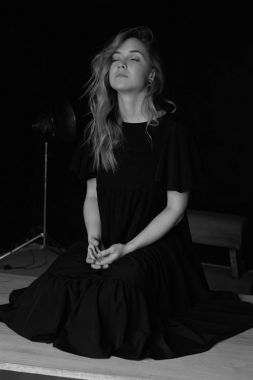 Trajik gizemli bir kadeh dizlerinin üstüne oturan siyah şık elbiseli sarışın çekici kadın sesleri kapalı gözler ile müzik dinlerken. Avrupa kadın zor günün ardından rahatlatıcı dikey portresi.