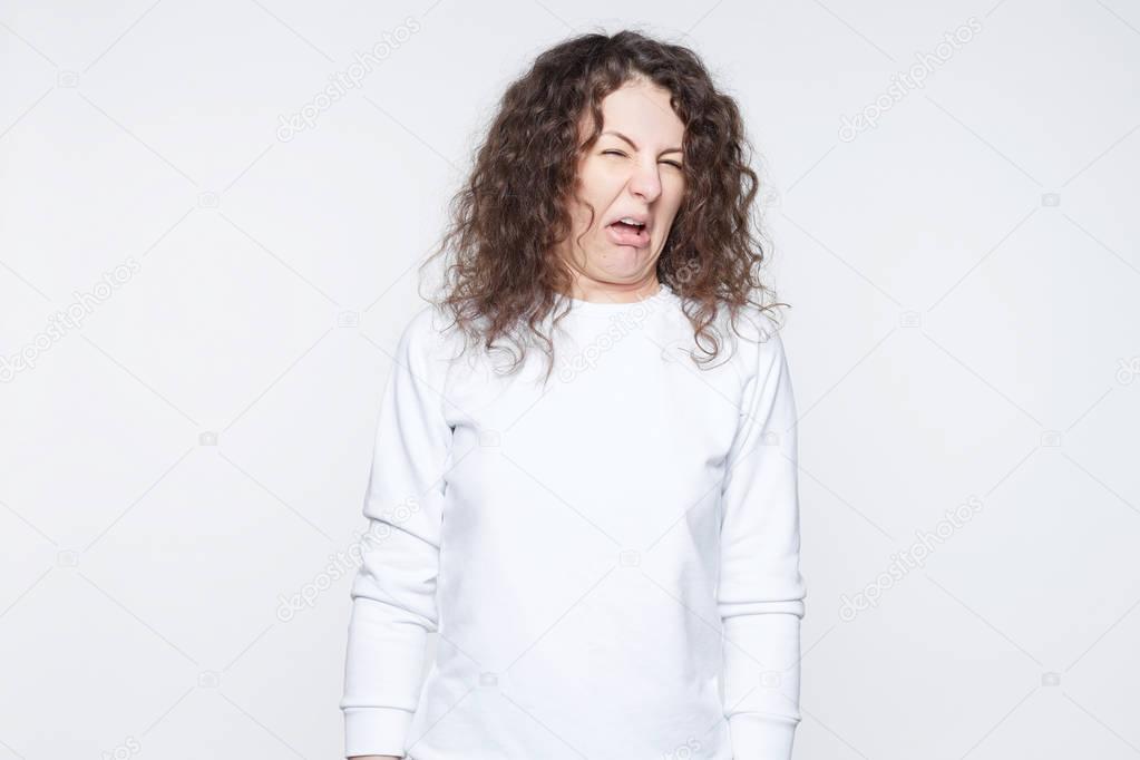 Brunette woman in casual clothes expressing disgust, unwillingness, dislike, disregard having tensive look frowning face.Caucasian woman with pleasant appearance looking indignant disgusting something