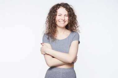 Olumlu insan yüz ifadeleri, duygular, tepki, duygular. Moda neşeli genç erkek kalbinin derinliklerinden gülüyor kıvırcık saç modeli ile beyaz duvar karnına ellerimi.