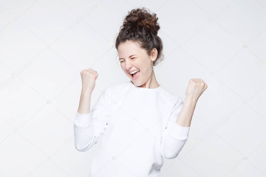 People, success, winning, victory, excitement, goals, determination and achievement concept. Joyful excited lucky young student woman cheering, celebrating success, screaming yes with clenched fists.