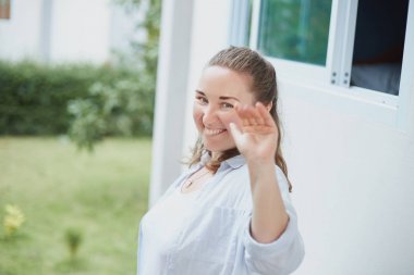 Olumlu insan duyguları, yüz ifadeleri, duygu, tutum ve tepki. Mavi gömlek ve el sallayarak, uzaklara kameraya bakarak veda, dost kibar genç Amerikalı kadın giyinmiş.