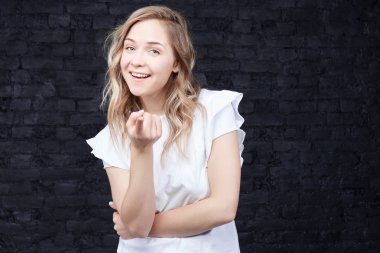 Hey siz! Moda hipster Bayan portresi vardır modaya uygun saç modeli, ön plana ile puan parmak sana, lider, casual beyaz t-shirt giymiş siyah tuğla duvarın üzerinden izole seçer. Olumlu duygular.