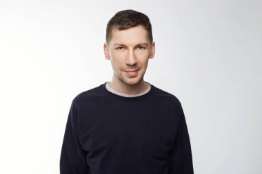 Kurnaz zor göz, gizemli bir şekilde gülümseyerek olan bir göz ile yanıp sönen çekici genç Kafkas çalışanla boş duvara doğru ve şık saç kesimi ayakta. Entrikacı ve komplo kavramı.