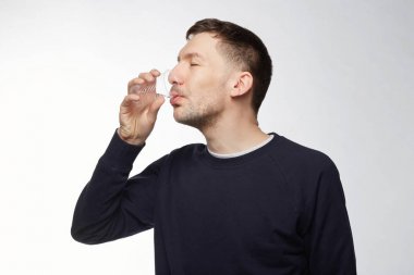 Pozitif genç susuz erkek uzun eğitimden sonra Mavi Bombacı giyen plastik bardaktan su içer, spor düşkün varlık olarak iyi bir ruh hali var, zevk gözlerinden kapatır. Etkin ve sağlıklı yaşam tarzı.