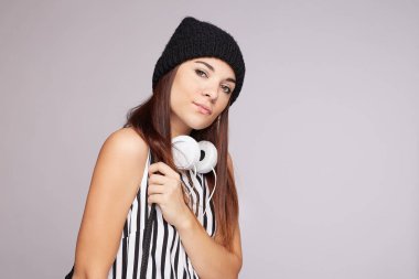 Hoş görünümlü genç bayan turist pozları, sokakta sakin bir yüz ifadesi, iyi duygular ifade eden, şık bir şapka ve çizgili bluz giyen, gri duvarda izole edilmiş. Yaşam tarzı kavramı