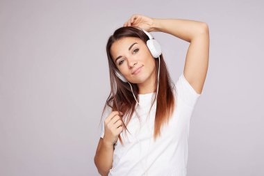 Genç, melez, bronz tenli, mutlu bir bayan. Her türlü hoş melodiyi seviyor. Dans ediyor, hareketler yapıyor, kulaklık takıyor, kameraya bakıyor.