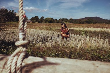 Tayland 'ın kuzeyindeki pirinç tarlalarında sallanan kahverengi saçlı kadın görüntüsü. Şapkalı ve kareli gömlekli bir kadın dağların ve ormanların harika manzarasına hayran, zaman geçiriyor. 