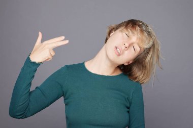 Sarışın bir kadının hareket halindeki otantik portresi tabanca hareketi yapar, tapınağa ateş eder, intihar işareti gösterir, çılgın bir görünümü vardır, günlük kıyafetler giyer, gri arka plana karşı modeller, kendini öldürür.. 