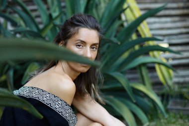 Ormanda kaktüslerle çevrili çekici beyaz bir kadının özgün doğal yakın plan portresi, kameraya şehvetli bir şekilde bakıyor, kahverengi gözleri, yumuşak, temiz bir teni var, anın tadını çıkarıyor. Güzellik konsepti.