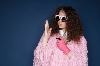 Şen şakrak kıyafetli şık bir bayan, bir elinde lastik eldivenle ev partisine hazırlanıyor, diğer elinde dezenfektan var, çevreyi alkol spreyiyle dezenfekte ediyor. Kendini koruma kavramı.