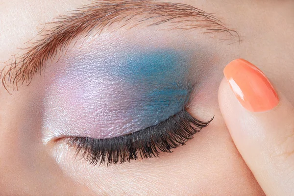 Esfumaçado olho azul compõem com o dedo com esmalte de unhas laranja — Fotografia de Stock