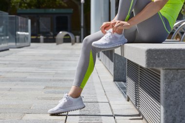 Kadın çalışan açık, güneş ışığı önce ayakkabı bağcığı bağlama